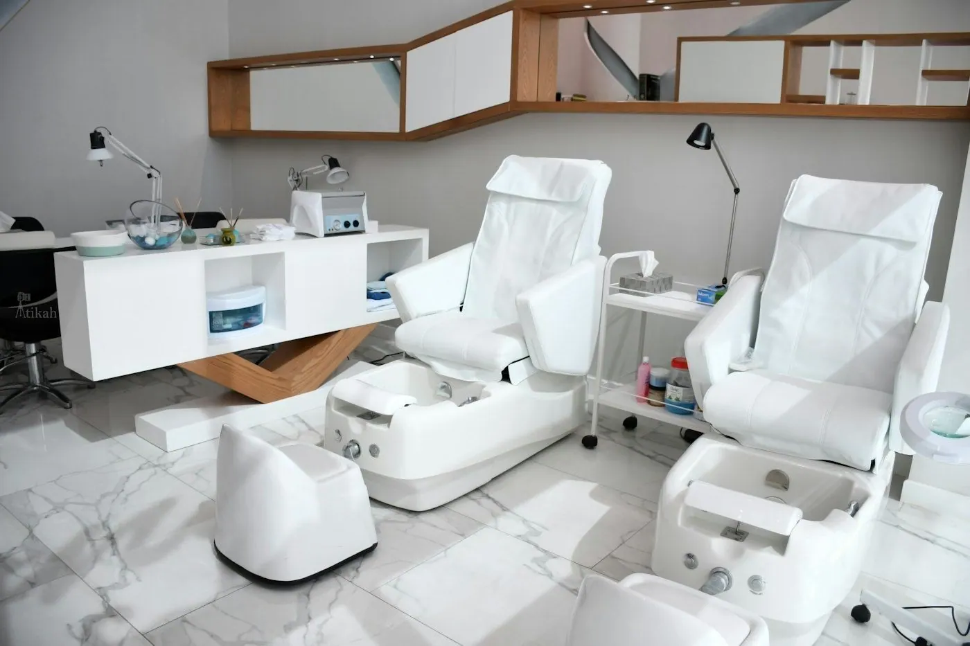 Row of white pedicure chairs in a bright salon