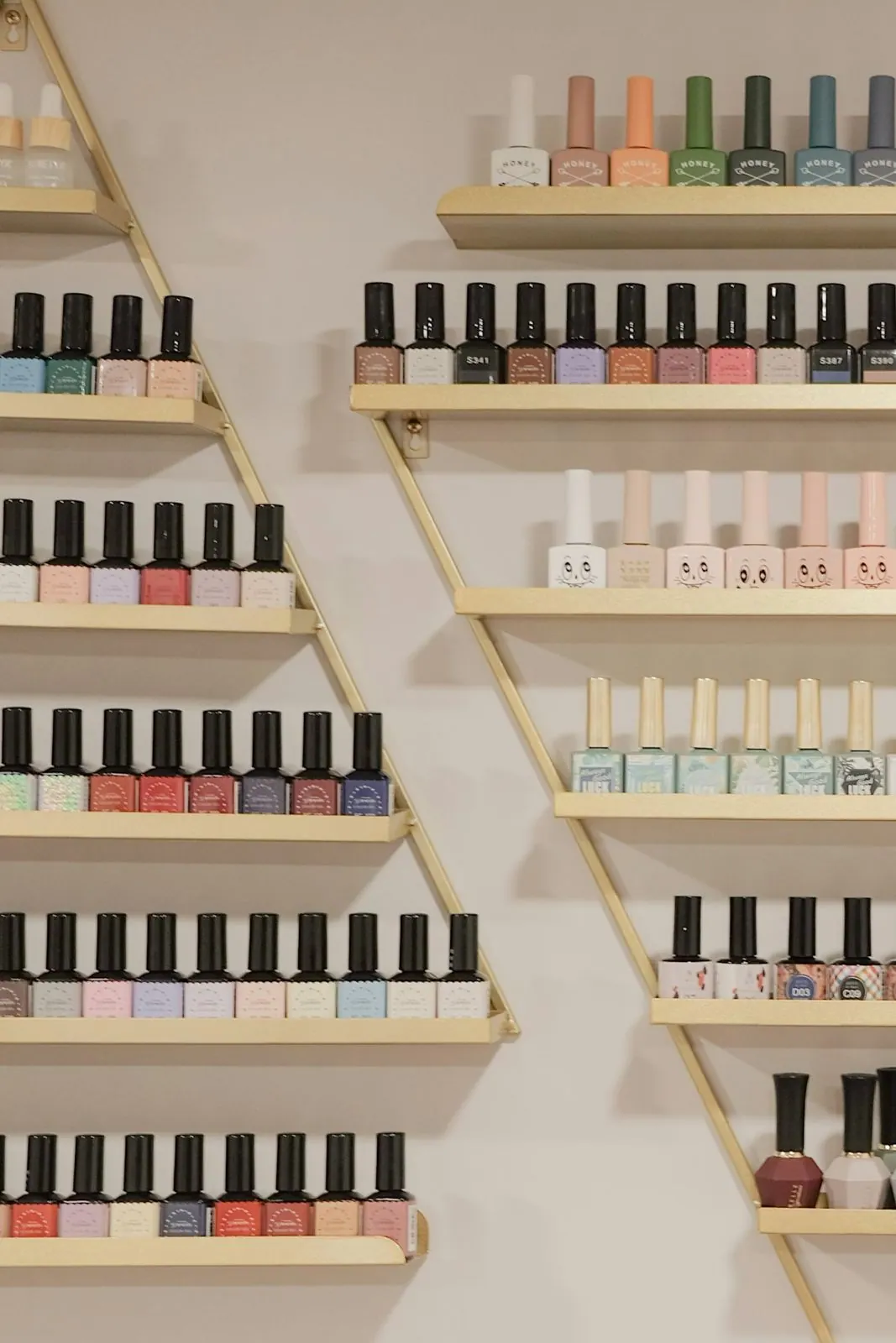 Wall of nail polish bottles on gold shelves